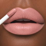 close-up lip image of a model with a medium dark skin tone wearing Runway Rogue Velvet Glam Long Wear Liquid Lipstick in Minimalist, a matte soft nude with a touch of blush